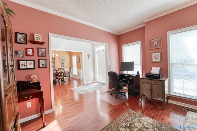 office with visible vents, a textured ceiling, hardwood / wood-style floors, an inviting chandelier, and crown molding