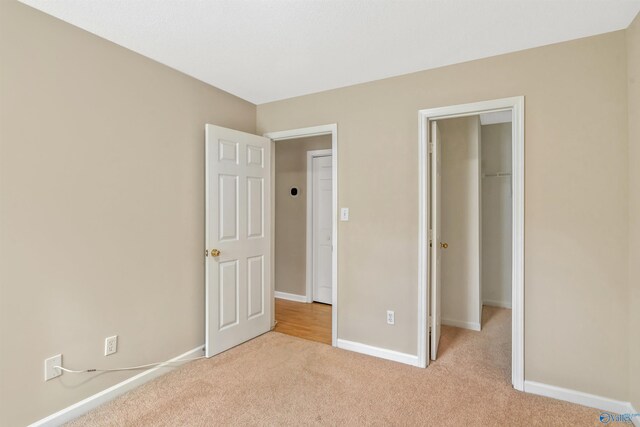 123 Otter Trl, Huntsville, AL 35824 - unfurnished bedroom featuring carpet, a walk in closet, baseboards, and a closet