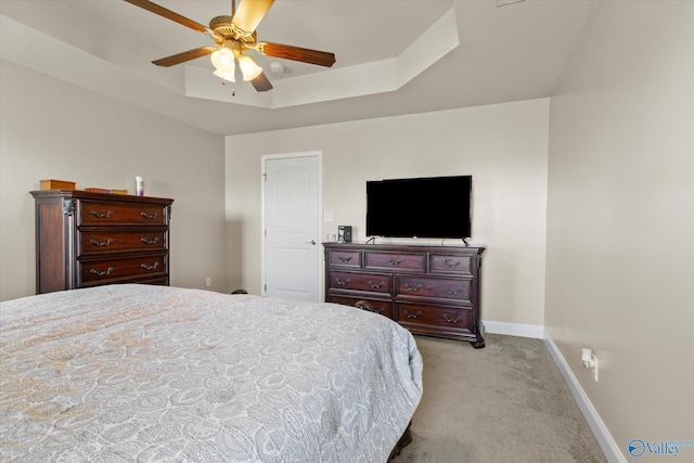 carpeted bedroom featuring ceiling fan and a raised ceiling