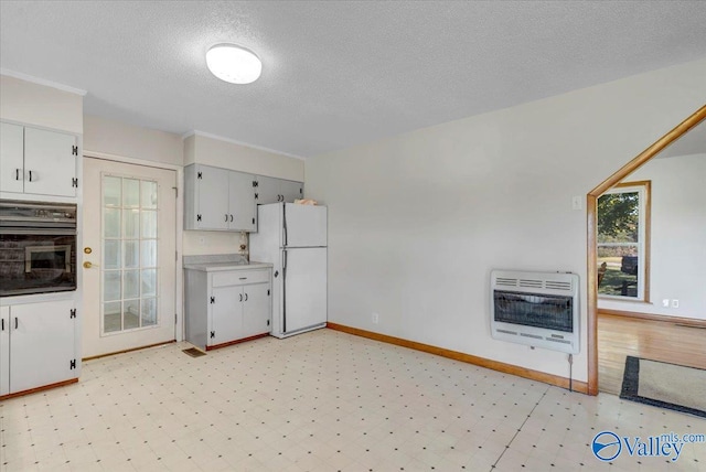 kitchen featuring a textured ceiling, oven, heating unit, and white refrigerator