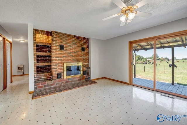 unfurnished living room with ceiling fan, a textured ceiling, heating unit, and a fireplace