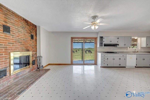 kitchen featuring ceiling fan, white dishwasher, a fireplace, gas cooktop, and sink