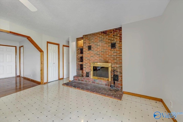 unfurnished living room with a textured ceiling and a brick fireplace