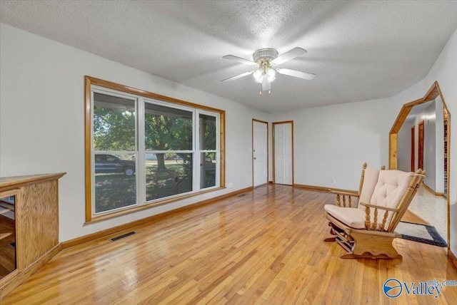 sitting room featuring a textured ceiling, light wood-type flooring, and ceiling fan