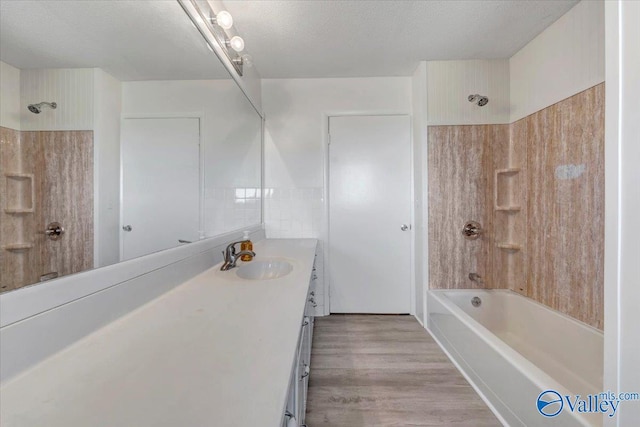 bathroom with vanity, a textured ceiling, wood-type flooring, and shower / washtub combination