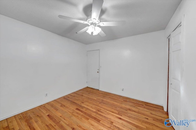 spare room with a textured ceiling, light wood-type flooring, and ceiling fan