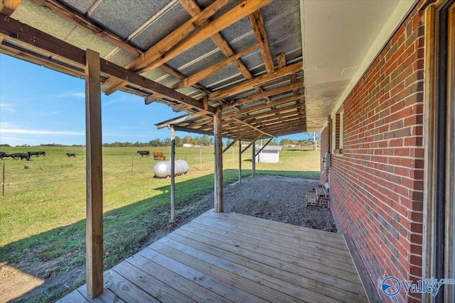 wooden terrace featuring a rural view and a yard