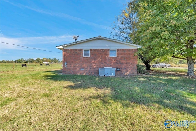 view of property exterior with central AC and a lawn