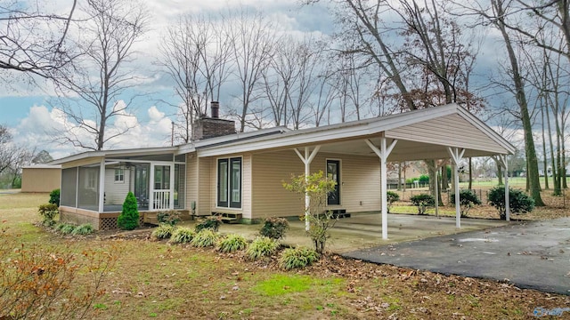 back of property with a carport and a sunroom