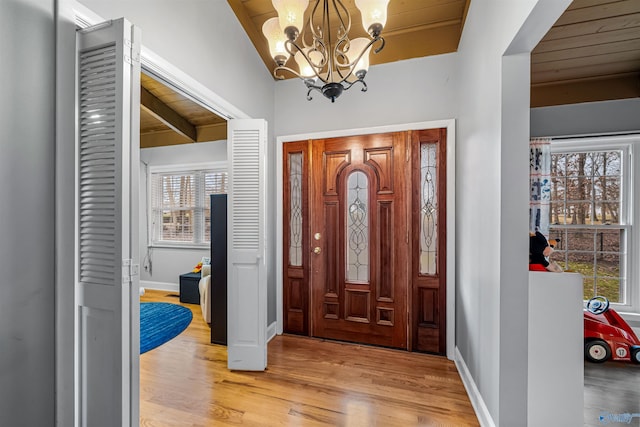 foyer entrance featuring wooden ceiling, a wealth of natural light, light hardwood / wood-style flooring, and vaulted ceiling with beams