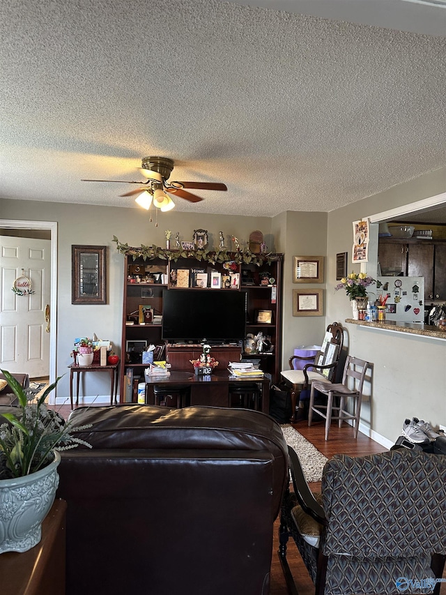 living area featuring wood finished floors, a textured ceiling, and ceiling fan