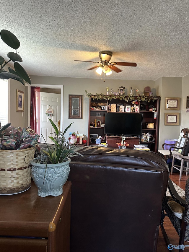 living area featuring a textured ceiling, wood finished floors, and a ceiling fan