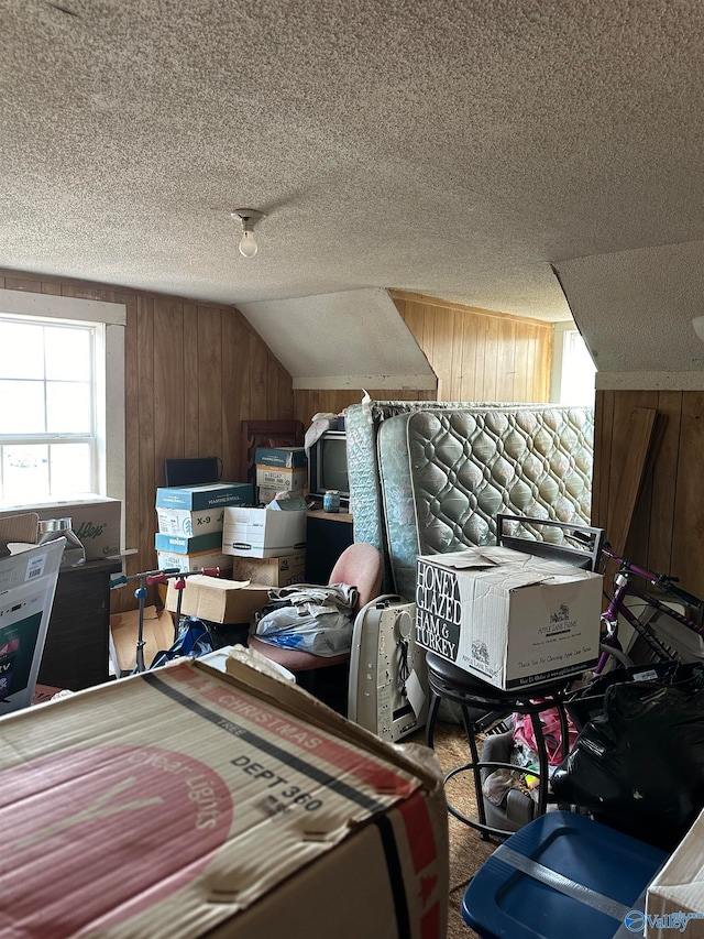 carpeted bedroom with vaulted ceiling, wood walls, and a textured ceiling