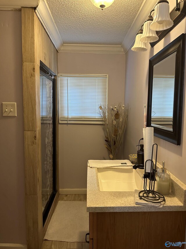 bathroom with vanity, hardwood / wood-style floors, ornamental molding, walk in shower, and a textured ceiling