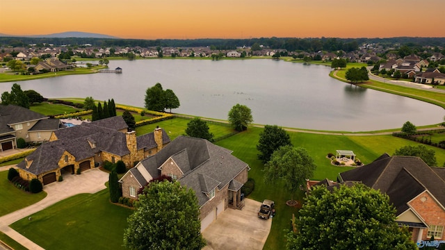 aerial view at dusk featuring a residential view and a water view