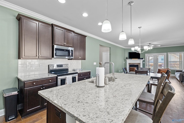 kitchen with a sink, open floor plan, stainless steel appliances, crown molding, and light wood finished floors