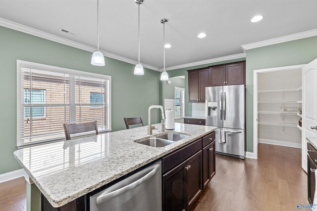 kitchen featuring visible vents, dark brown cabinetry, ornamental molding, stainless steel appliances, and a sink