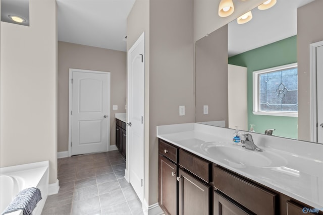 full bath featuring tile patterned floors, baseboards, a bathtub, and vanity