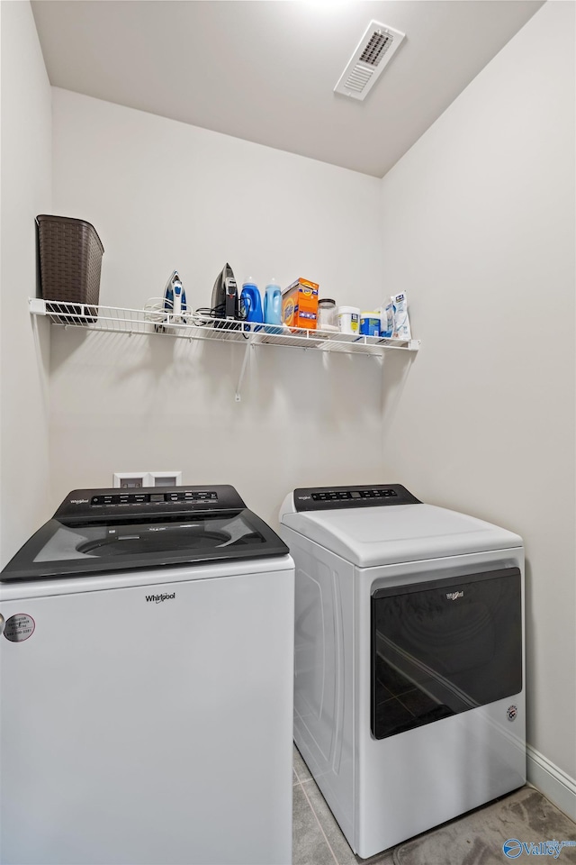 washroom featuring washing machine and clothes dryer, visible vents, and laundry area