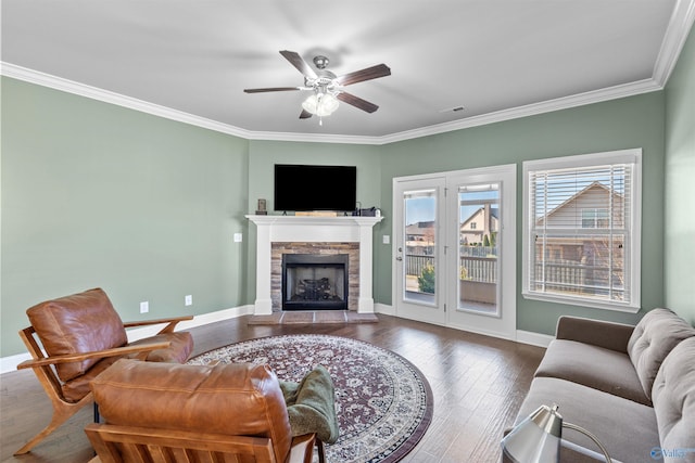 living room with a stone fireplace, baseboards, and wood finished floors