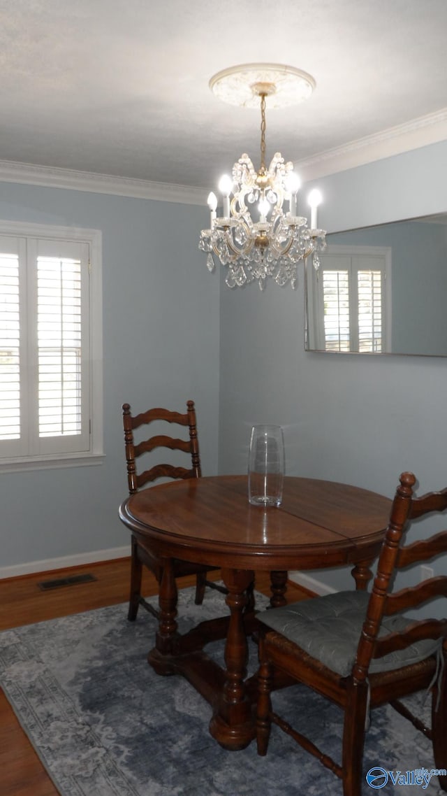 dining room with visible vents, wood finished floors, ornamental molding, and a healthy amount of sunlight