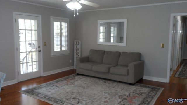 living area with wood finished floors, ornamental molding, baseboards, and ceiling fan