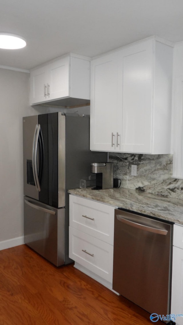 kitchen with white cabinetry, appliances with stainless steel finishes, light stone counters, and backsplash