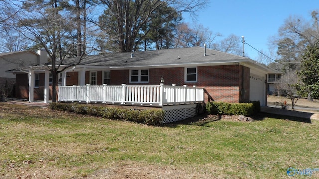 rear view of property featuring a garage, brick siding, a yard, and a wooden deck