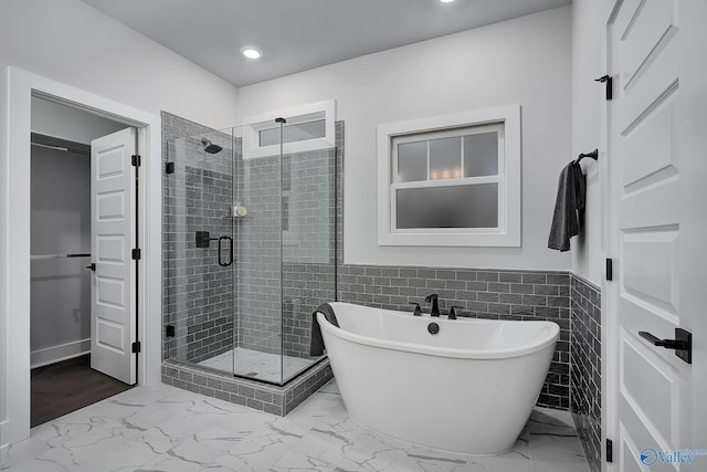full bathroom with marble finish floor, wainscoting, a freestanding tub, and a shower stall