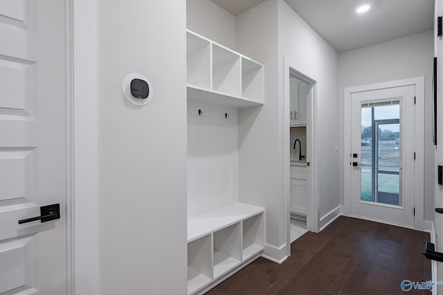 mudroom with dark wood-style flooring, baseboards, and a sink