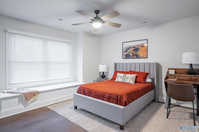 bedroom featuring baseboards, ceiling fan, wood finished floors, and visible vents