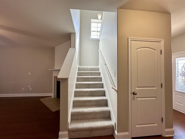 stairway featuring plenty of natural light, wood finished floors, and baseboards