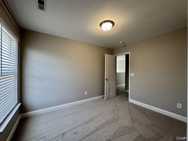 spare room featuring visible vents, baseboards, and light colored carpet