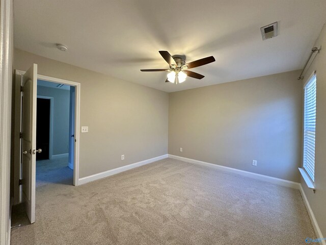 empty room with a ceiling fan, carpet, visible vents, and baseboards