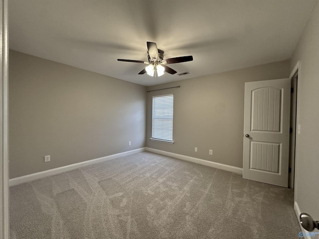 carpeted spare room with a ceiling fan, visible vents, and baseboards