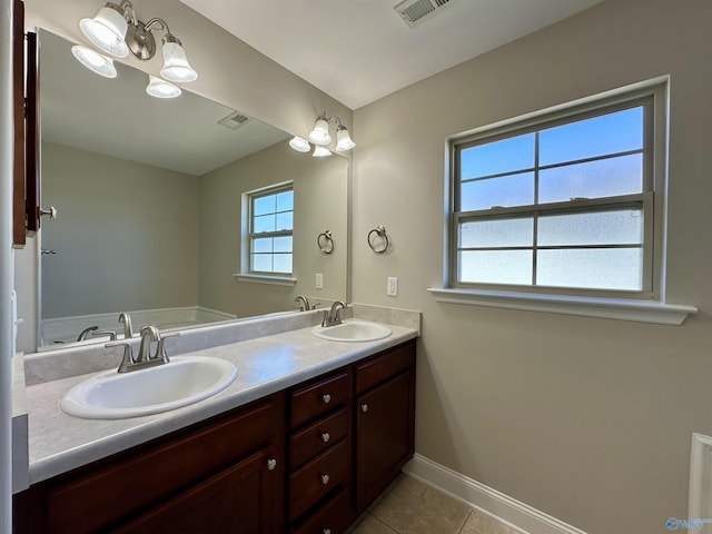 bathroom featuring baseboards, double vanity, a sink, and tile patterned floors