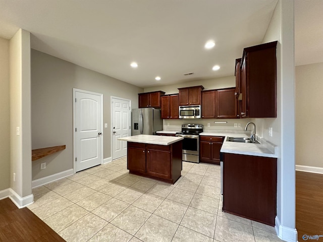 kitchen featuring a kitchen island, appliances with stainless steel finishes, light countertops, and a sink