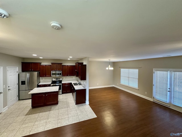 kitchen with light countertops, light wood-style flooring, appliances with stainless steel finishes, open floor plan, and a kitchen island