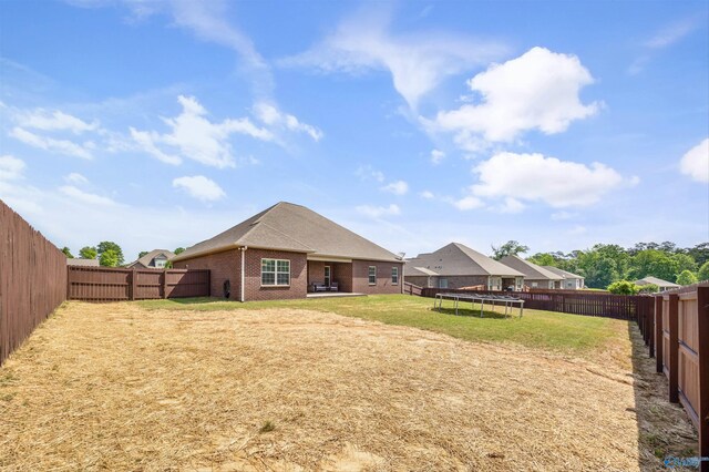 506 Foxridge Dr SW, Hartselle, AL 35640 - back of house featuring brick siding, a fenced backyard, a trampoline, and a yard