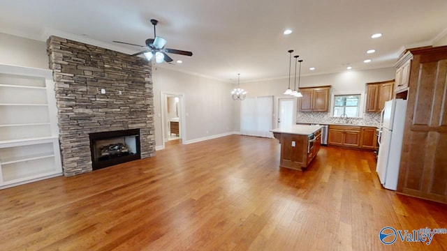 kitchen featuring pendant lighting, light wood-type flooring, white refrigerator, a fireplace, and a kitchen island