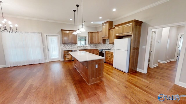 kitchen featuring light hardwood / wood-style flooring, white refrigerator, a kitchen island, and decorative light fixtures