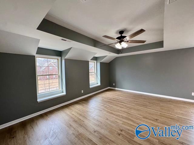 additional living space with hardwood / wood-style flooring, vaulted ceiling, and ceiling fan