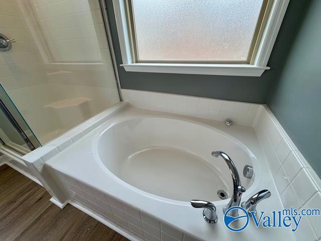 bathroom with hardwood / wood-style flooring and plus walk in shower