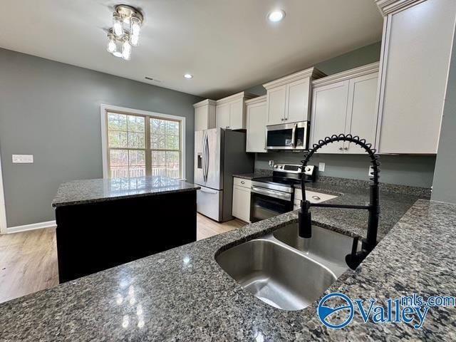 kitchen with dark stone countertops, a center island, white cabinets, and appliances with stainless steel finishes