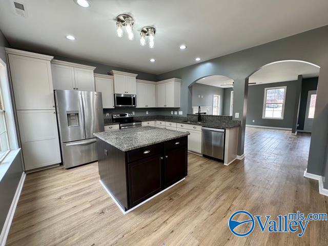 kitchen featuring sink, appliances with stainless steel finishes, white cabinetry, a kitchen island, and light wood-type flooring