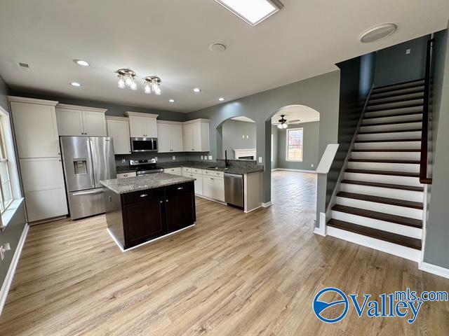 kitchen with sink, light hardwood / wood-style flooring, appliances with stainless steel finishes, a kitchen island, and white cabinets