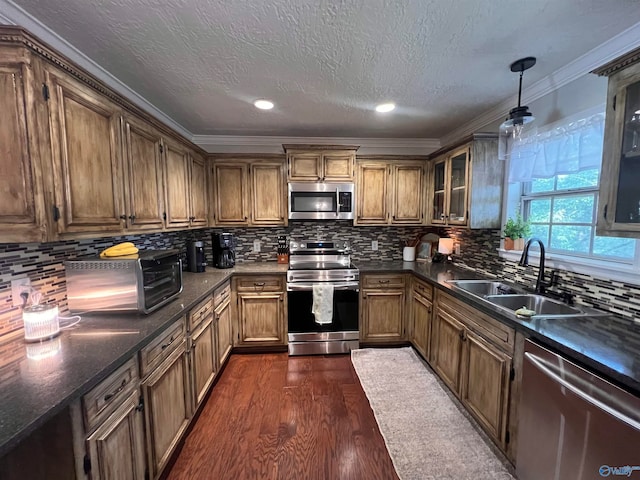 kitchen featuring hanging light fixtures, dark hardwood / wood-style flooring, stainless steel appliances, ornamental molding, and sink