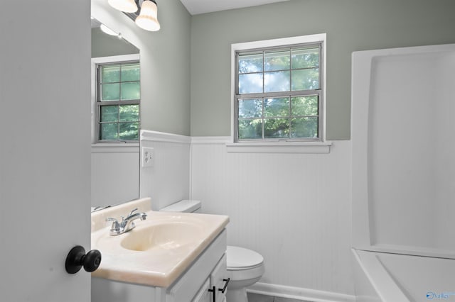 bathroom featuring toilet, vanity, and wainscoting