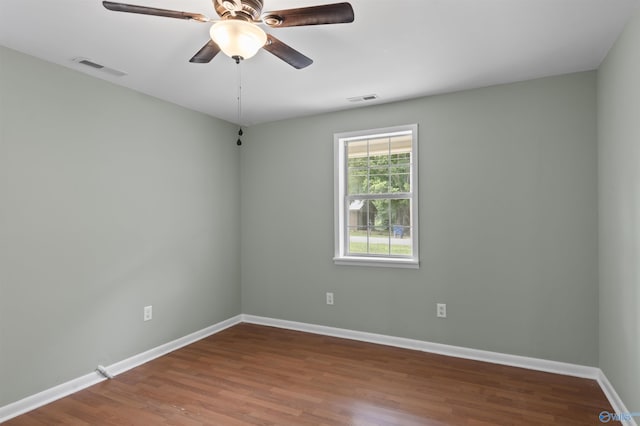 spare room featuring visible vents, ceiling fan, baseboards, and wood finished floors