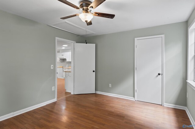 unfurnished bedroom featuring attic access, baseboards, and wood finished floors